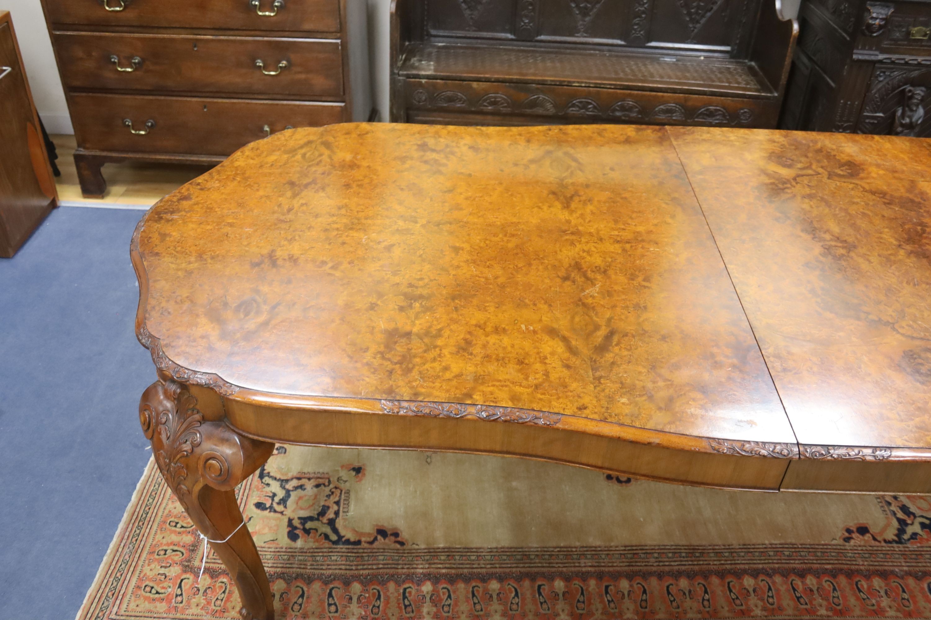 A Queen Anne revival burr walnut shaped oval extending dining table, 272cm extended, one spare leaf, width 106cm, height 75cm